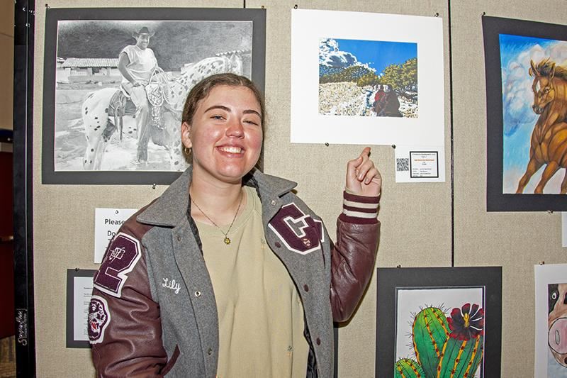 Cy-Fair High School Class of 2022 graduate Lily Forbes takes a picture next to her art piece.